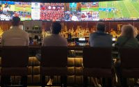 a group of people sitting at a bar watching tv